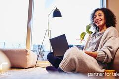 una mujer sentada viendo su computadora. 