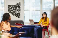 dos mujeres platicando en la oficina.