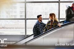 Gente sonriente en una escalera mecánica de una estación de tren