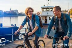  Dos jóvenes bajan de un ferry en bicicleta y disfrutan de un día soleado junto al agua. Generado por IA.