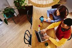 2 personas sentadas en un escritorio viendo una laptop
