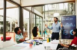 3 personas en una reunión viendo al frente a 1 persona que esta explicando algo.