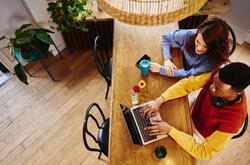2 personas sentadas en un escritorio viendo una laptop