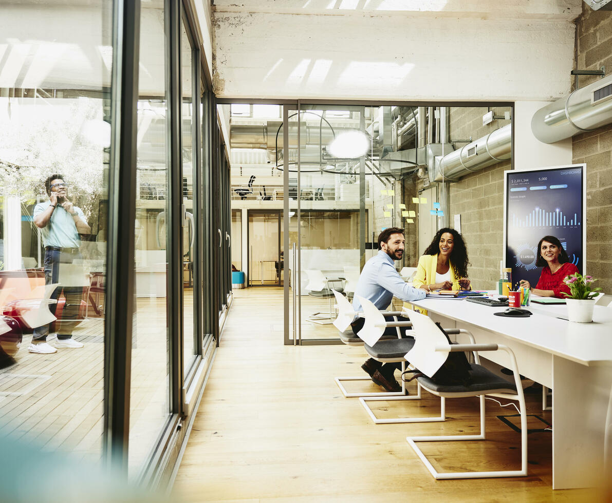 Three colleagues having a meeting in a meeting room, while one colleague is making a call outside the room.
Three colleagues having a meeting in a meeting room, while one colleague is making a call outside the room.