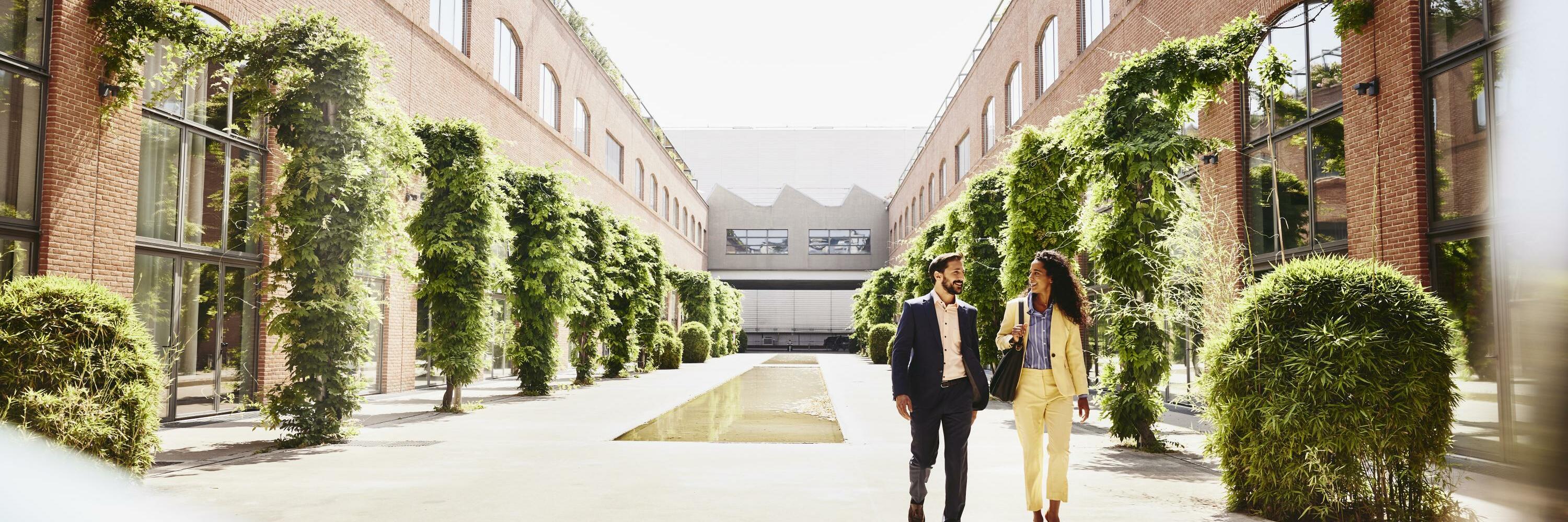 Man and woman walking outside between office buildings.