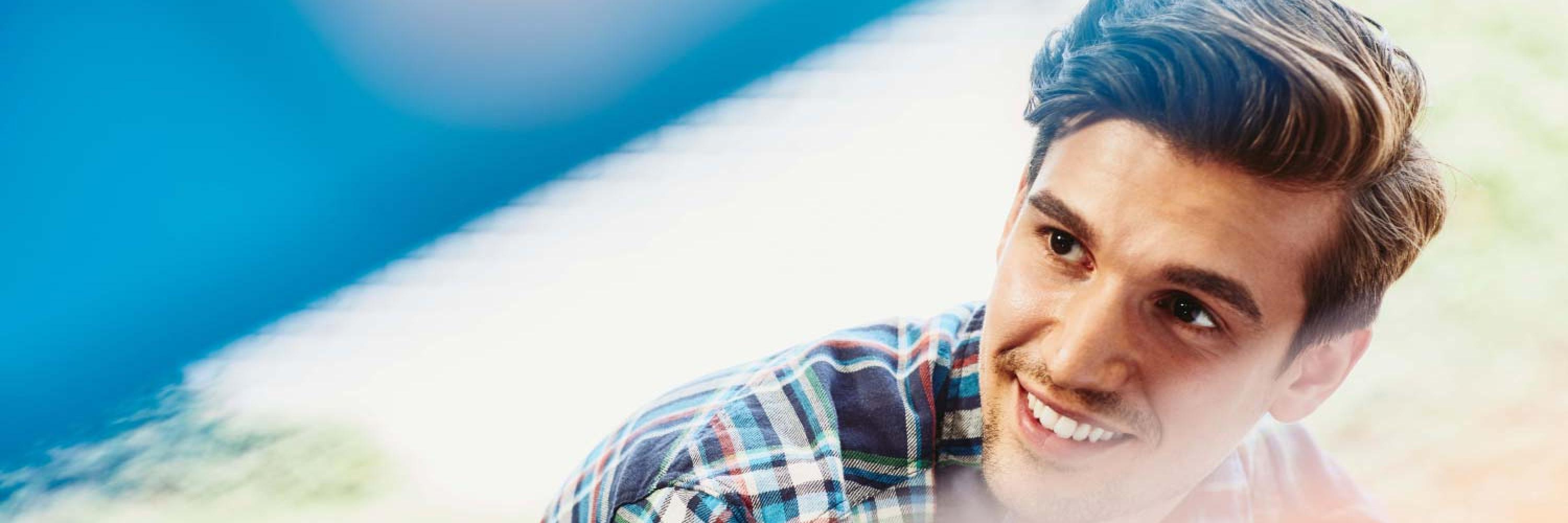 hombre con camisa de cuadros sonriendo por tener un nuevo empleo
