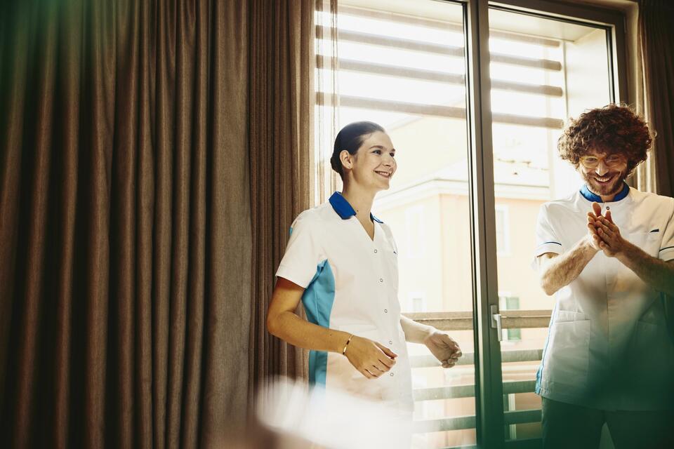 Two colleagues chatting, working housekeeping in a hotel room.